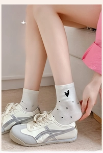 Detail of white knit socks with black polka dots and embroidered heart with sneakers