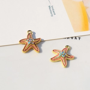 Detailed view of starfish pendants with pink enamel, crystals and golden bead edges