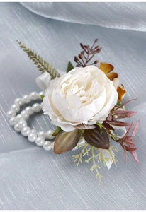 Detailed view of a white artificial flower wrist corsage with double-strand pearl bracelets