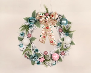 Detail of flocked Christmas wreath with blue and pink ornaments and a gnome pattern bow