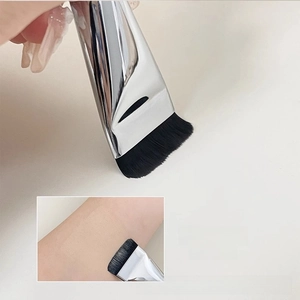 Detailed close-up of flat foundation brush with dense black fibers and silver handle