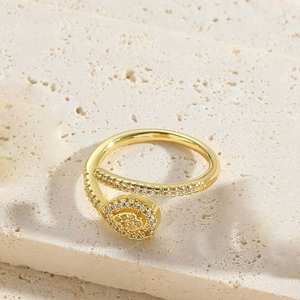 Close-up of golden adjustable snake ring with sparkling zircon stones on stone background
