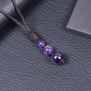 Macro shot of 16mm natural amethyst beads on a brown braided cord with textured detail