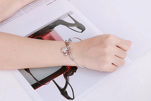 Silver stainless steel bracelet featuring guitar pendant on lifestyle fashion magazine background