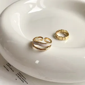 Detailed view of gold stacked rings with gray enamel inlay and textured finish on a ceramic tray