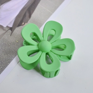 Close-up of green matte flower hair claw clip on a minimalist lifestyle background