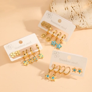 Detail view of gold stainless steel earring set with clover and star charms on cards
