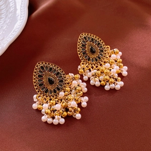 Detail view of vintage gold tassel earrings with pearls and black stones on silk background