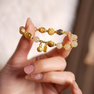 Gros plan d'un bracelet en perles de citrine avec pendentif porte-bonheur doré caractère Fu