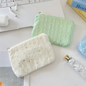 Detail of sequin chiffon flower coin purses in mint green and cream on a desk