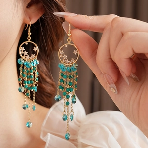 Détail de créoles dorées vintage avec perles turquoise et pompons frangés en cristal
