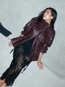Close-up of burgundy leather jacket texture and black lace dress detail in street style