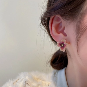 Macro detail of a golden flower earring with purple gems worn by a model