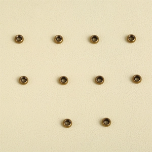 Macro detail of ten round bronze metal beads for DIY jewelry making on beige texture