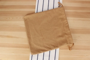 Macro shot of light brown linen drawstring pouch for woven bag storage on wooden table