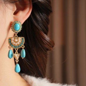 Nahaufnahme von Vintage-Ohrhängern mit Türkissteinen und blauen Kristallen am Modell