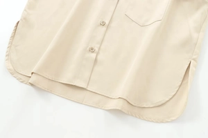 Detail of light beige twill shirt showing curved hem, pocket, and matching buttons