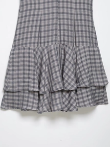 Close-up of grey and black plaid dress with double-layered ruffled hem and fabric texture