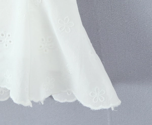 Detail showing white lace floral embroidery and scalloped edge on the skirt hem