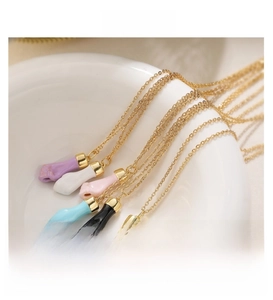 Colorful enamel hand pendants in various colors inside a ceramic bowl on gold chains