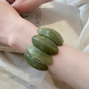 Detailed view of an olive green marble resin stretch bracelet worn on a female wrist