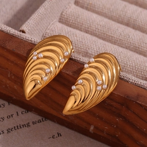 Gros plan sur des boucles d'oreilles coquillage dorées avec perles et texture froissée