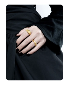 Detail of vintage gold-toned rings featuring textured wave and relief portrait on model