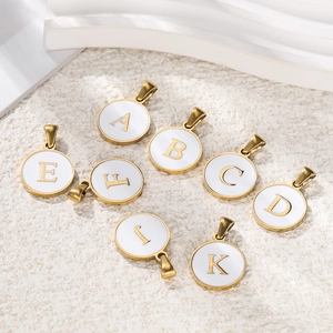 Macro shot of circular gold alphabet pendants with white enamel and golden letters