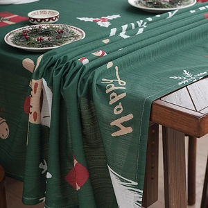 Green Christmas tablecloth with reindeer and snowflakes on a festive wooden dining table