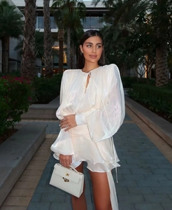 Detailed view of the pearlescent satin texture and ruffled hem on white lantern sleeve dress