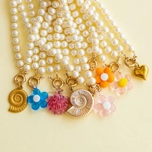 Macro view of white faux pearl necklaces with assorted gold and resin charms