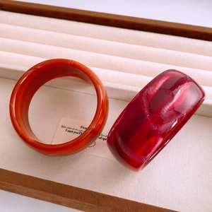 Détail de bracelets en acrylique rouge et orange avec texture marbrée sur plateau