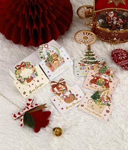 Flat lay of seven gold-stamped Merry Christmas cards on white plush background