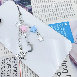 Close-up of Y2K star and cross phone charm with silver metal chain on a white smartphone