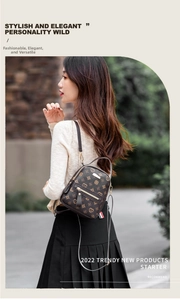 Outdoor shot of a mini dark brown faux leather backpack with heart monogram pattern