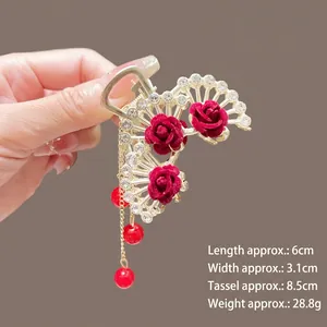 Détail de la pince à cheveux dorée avec roses en velours rouge et glands de perles