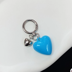 Detail of blue resin heart keychain with silver metal rings on a white plate
