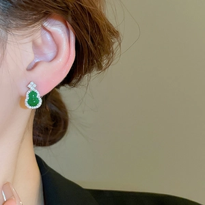 Close-up of elegant green gourd drop earrings with rhinestones worn by a model