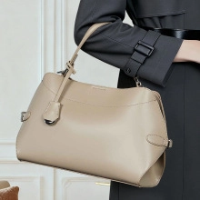 Detail of premium beige leather handbag featuring a slim handle and sleek silver buckles