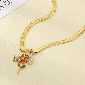 Close-up of gold snake chain necklace with red rose, heart zircon and clover pendants