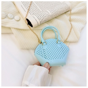Close-up of a mini light blue pearl shell jelly bag with golden chain and bead texture