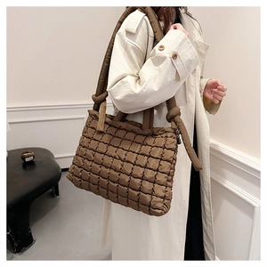 Detail of a brown quilted puffer tote bag featuring knotted strap and nylon texture