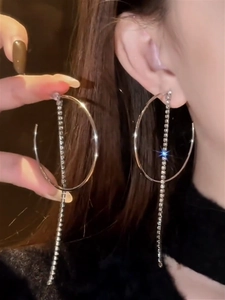Detail of silver hoop earrings with long sparkling tassel and shimmering rhinestones