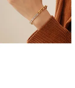 Detail of 18K gold plated U-link chain bracelet with rectangular zircon accents on wrist