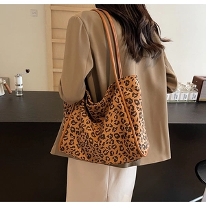 Detail of a large leopard print tote bag featuring brown leather shoulder straps