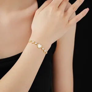 Gold plated bracelet with heart shell and cubic zirconia stones on female wrist