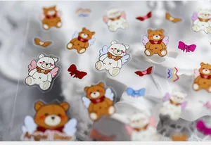 Detail showing Angel Bear nail art stickers with wings and red bow designs for DIY