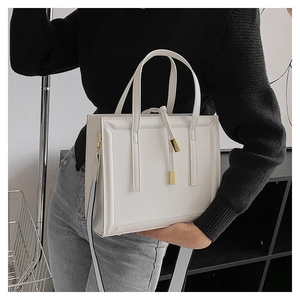 Detailed view of white leather crossbody bag with gold hardware and wide shoulder strap