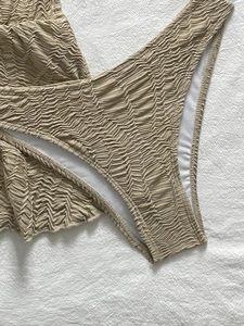 Nahaufnahme des beigefarbenen Seersucker-Stoffs und der Nähte eines dreiteiligen Bikinis
