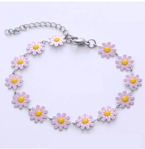 Détail d'un bracelet en acier inoxydable avec de délicats charm's marguerites roses et jaunes